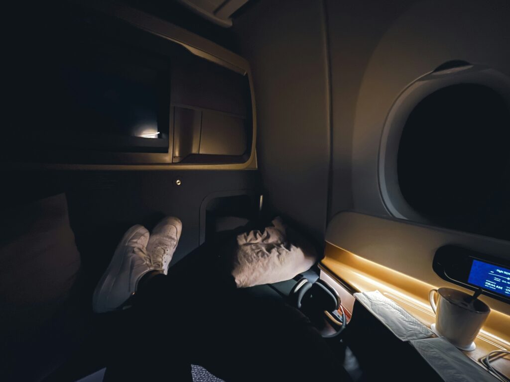 persons bottom half while they are sleeping on a plane, probably on a travel pillow