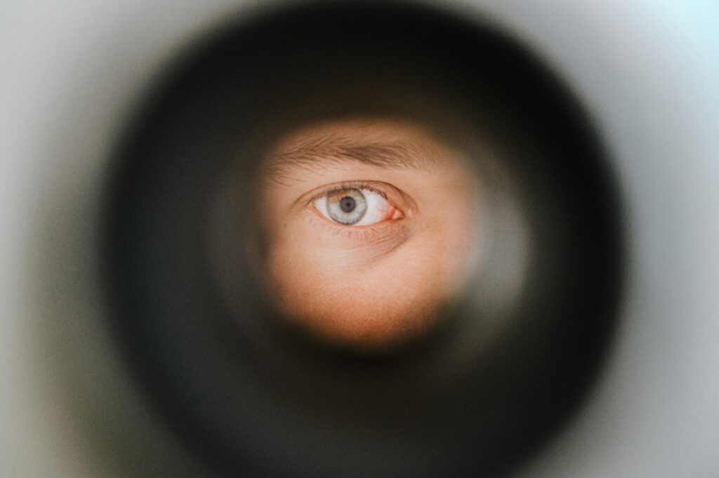 person looking through peephole, they have light green/grey eyes
