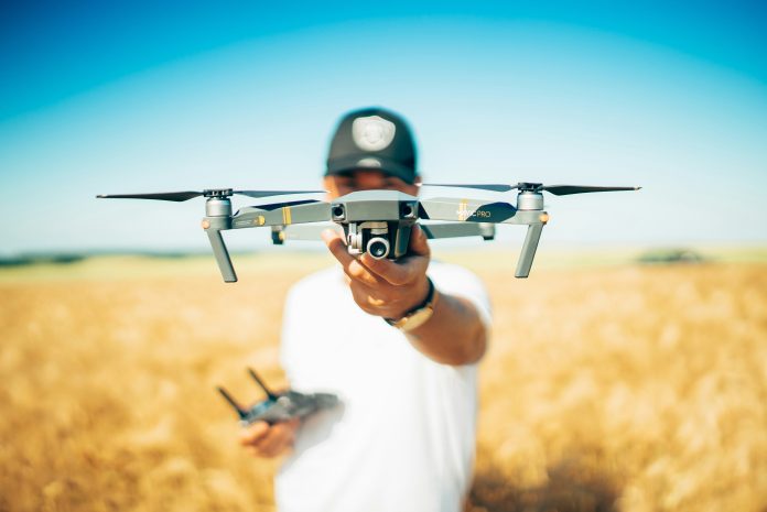 Man in a wheat field holding a drone up in his hand